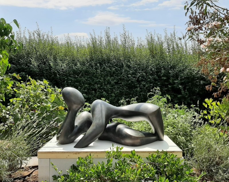 Bronze sculpture "In Harmony", dark green/black patina, placed on a plinth in a lush green garden