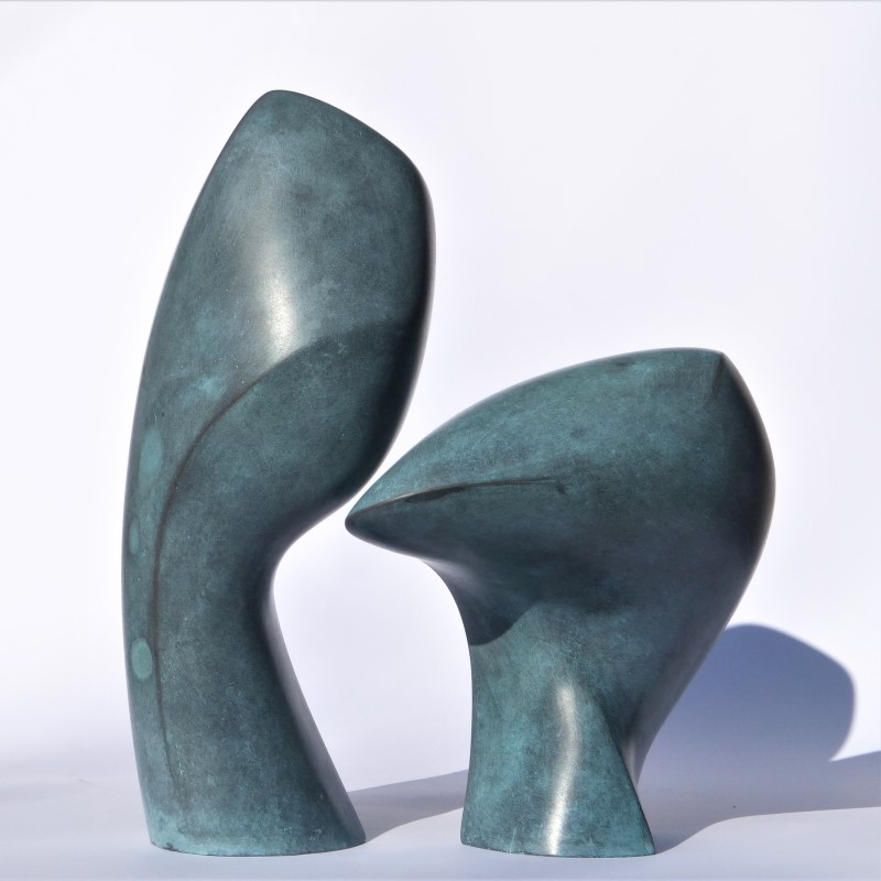 Two abstract sculptures corresponding with each other, smooth green patinated surfaces and round forms.