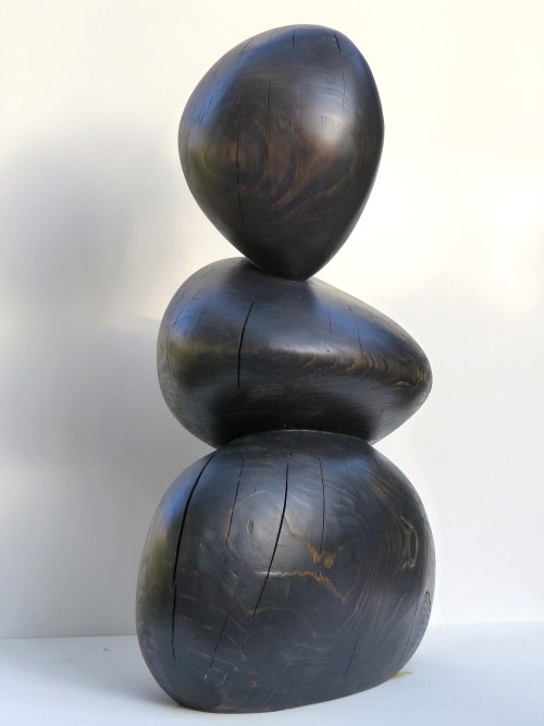 Abstract sculpture made of black glazed spruce wood. Three round shapes balance each other.