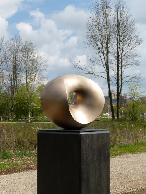 Auf der Landesgartenschau Ellwangen: Abstrakte runde Skulptur mit einem Loch in der Mitte, matt gold geschliffen.